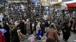 Orang-orang memilih sepatu dan sandal di pasar terbuka di ibu kota Yaman, Sanaa (2/5/2021). Umat Muslim di Yaman memenuhi pasar menjelang liburan Idul Fitri yang menandai akhir bulan suci Ramadhan. (AFP/Mohammed Huwais)