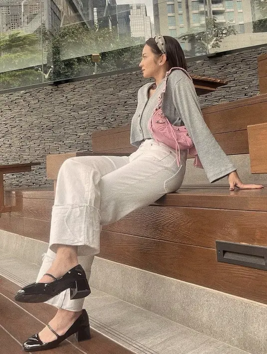 <p>Enzy tampil dengan cardigan crop top abu-abu dipadukan celana denim putih serta kitten heels stiletto hitamnya. Agar tak membosankan, ia menambahkan tas pink untuk ootdnya kala itu. @enzystoria</p>