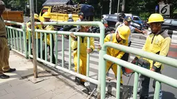 Petugas membongkar pagar pembatas besi di kawasan Pinang Ranti, Jakarta, Senin (11/2). Zebra cross yang berada di samping Tamini Square itu sempat jadi perbincangan lantaran terhalang oleh pagar besi hijau setinggi 1 meter. (Liputan6.com/Herman Zakharia)