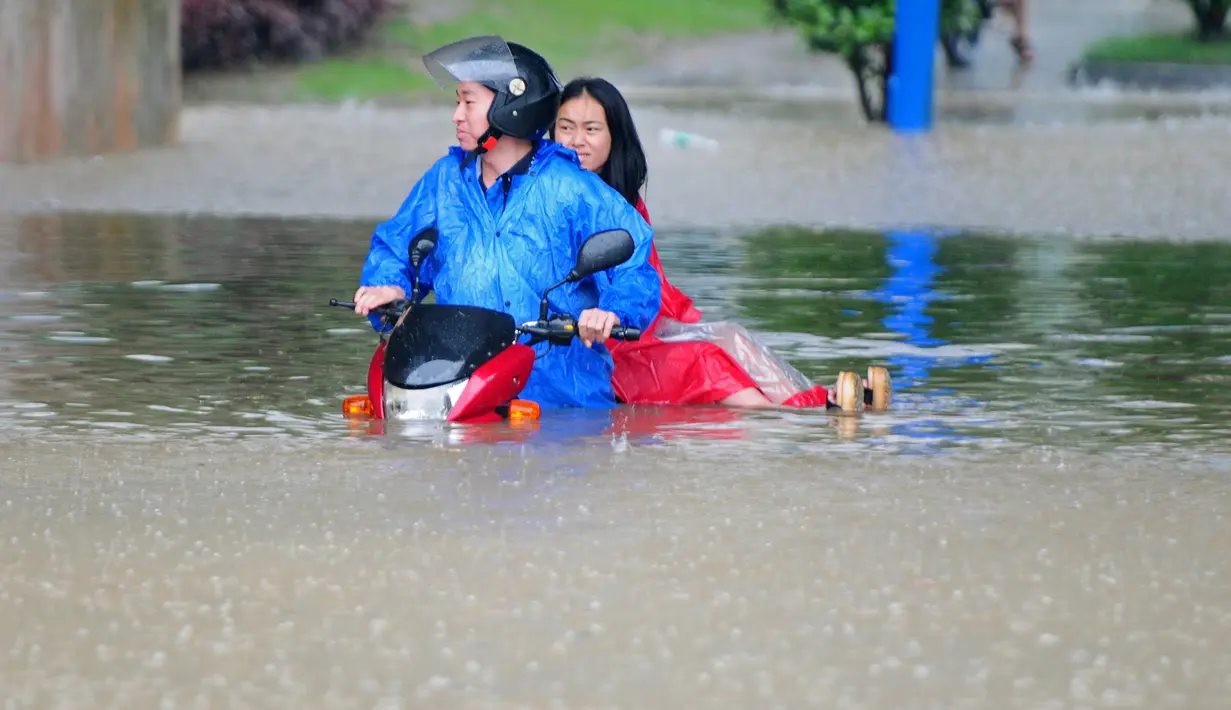 Pesepeda motor mencoba menerobos jalanan yang banjir di Jiujiang , Provinsi Jiangxi , Cina , (19/2). Hujan lebat terus-menerus membuat kawasan Kota Jiujiang banjir dan melumpuhkan lalu lintas. (REUTERS/ China Daily)