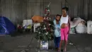Tatiani (kanan) dan anaknya Leonardo berpose disamping pohon Natal di Sao Paulo, Brasil, (18/12). Mereka adalah keluarga tunawisma yang tinggal di bawah jembatan. (REUTERS/Nacho Doce)