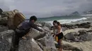 Orang-orang memungut sampah dari pantai Copacabana pada Hari Laut Sedunia di Rio de Janeiro, Brasil, Rabu (8/9/2022). Organisasi Route Brasil menyerukan agar orang-orang berkumpul untuk acara yang diberi nama "Pelukan Itu," dan untuk memungut sampah di pantai, untuk menarik perhatian pada pencemaran laut. (AP Photo/Silvia Izquierdo)