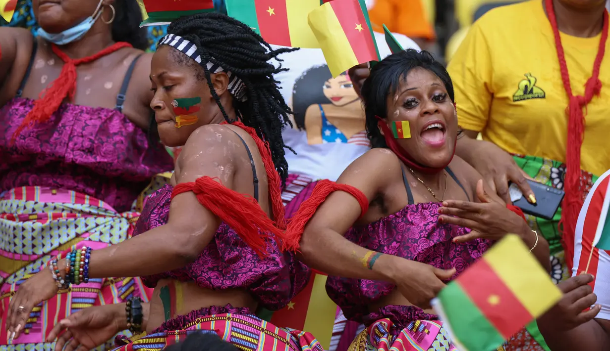 Dua suporter wanita Kamerun berjoget menjelang upacara pembukaan turnamen sepak bola Piala Afrika (CAN) 2021 di Stade d'Olembé di Yaounde (9/1/2022). Kamerun untuk kali kedua menjadi tuan rumah Piala Afrika setelah pada 1972. (AFP/Kenzo Tribouillard)