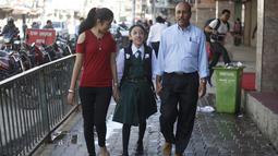 Mantan Dewi Nepal atau Kumari, Matina Shakya (tengah) berjalan ke sekolah ditemani ayahnya Pratap Man Shakya (kanan) dan saudarinya di Kathmandu (9/10). Sewaktu menjadi Kumari, Matina dirawat oleh pengasuh yang ditunjuk secara khusus.(AFP Photo/Gopen Rai)