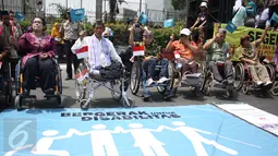 Penyandang disabilitas melambaikan bendera bertuliskan ‘Bergerak untuk Disabilitas’ saat Karnaval Budaya Disabilitas di kawasan Bundaran HI, Jakarta, Selasa (18/08/2015). (Liputan6.com/Gempur M Surya)  