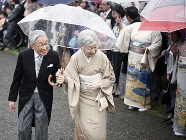 Kaisar Jepang Akihito dan Permaisuri Michiko menyambut para tamu saat pesta taman musim gugur di taman kekaisaran Akasaka Palace, Tokyo, Jumat (9/11). Kaisar dan Permaisuri tampil romantis dengan sepayung berdua saat hujan. (AP Photo/Eugene Hoshiko)