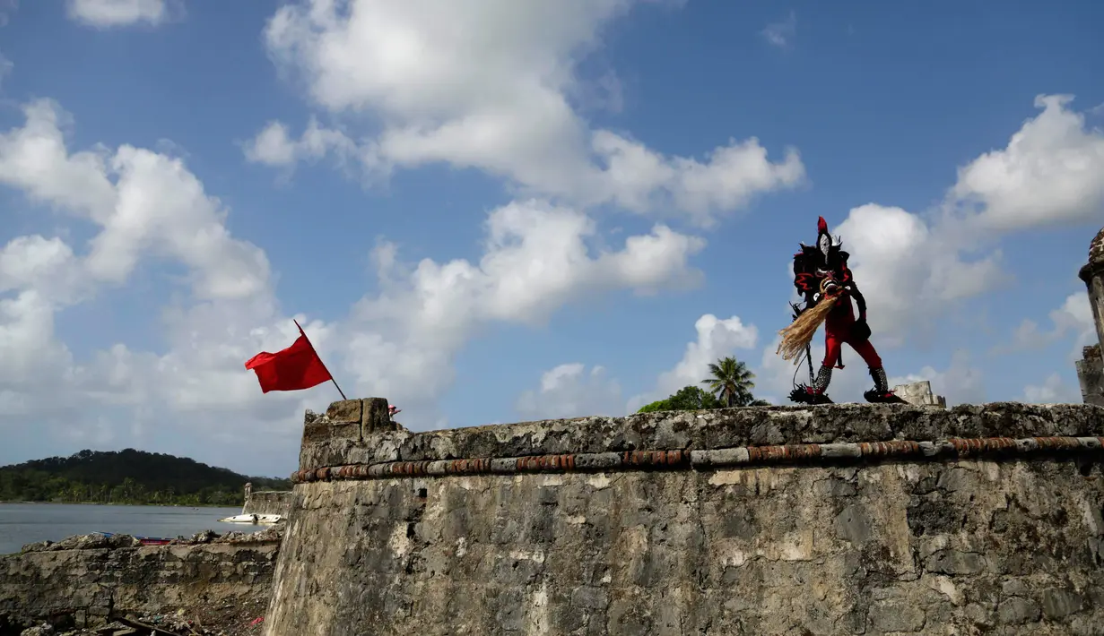 Seorang pria mengenakan kostum setan menari di dinding benteng San Jeronimo saat festival Congos and Devils di Portobelo, Panama (18/3). Festival ini digelar untuk melestarikan budaya dan menghormati nenek moyang mereka. (AP Photo/Arnulfo Franco)