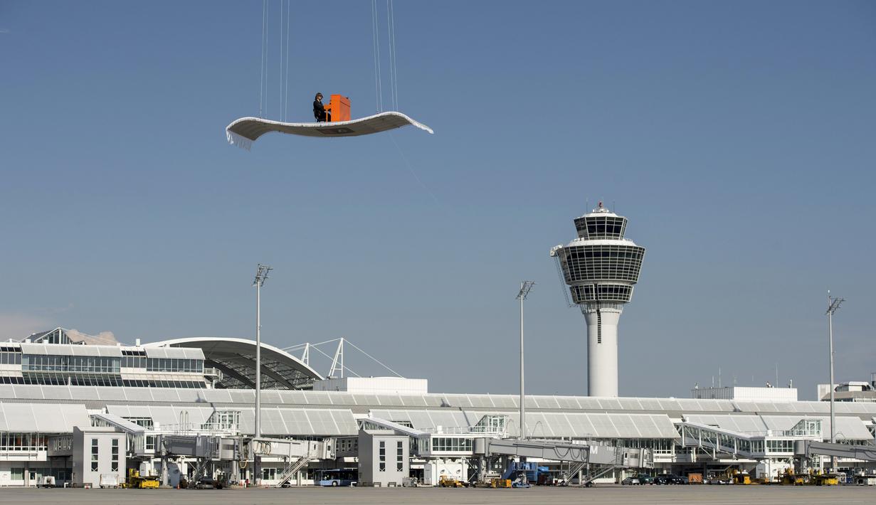 Aksi Stefan Aaron saat memainkan piano di atas 'karpet terbang' di bandara Munich, Jerman, Rabu (23/7/14). (REUTERS/Lukas Barth) 