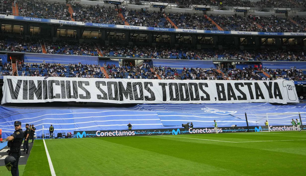 Spanduk bertuliskan "Kita semua Vinicius" terpasang pada laga lanjutan Liga Spanyol 2022/2023 antara Real Madrid melawan Rayo Vallecano pada Kamis (25/05/2023) dini hari WIB. Los Blancos memberikan aksi solidaritas sebelum laga tersebut setelah pemain Brasil itu menjadi korban rasisme pada Minggu (21/05/2023) lalu. (AP Photo/Manu Fernandez)