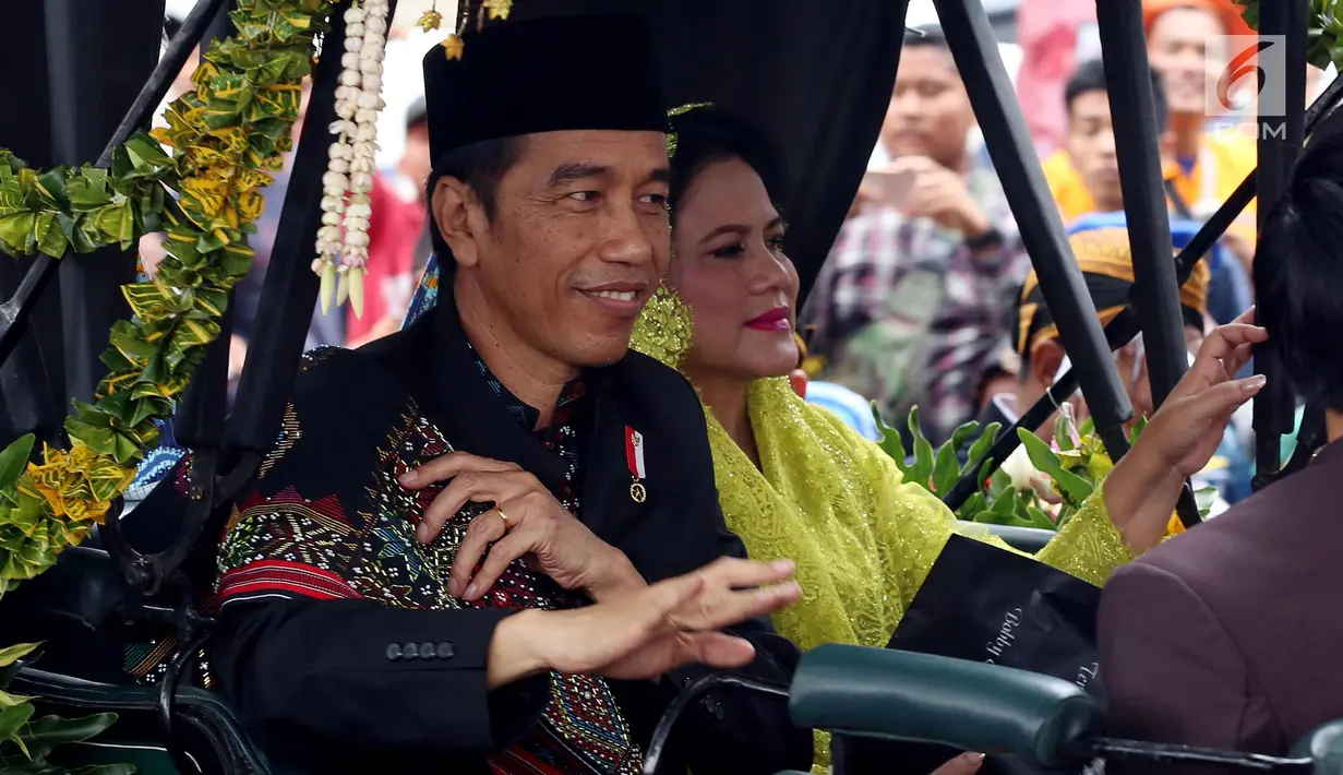 Presiden Joko Widodo bersama Ibu Negara Iriana menyapa warga saat kirab resepsi pernikahan Kahiyang Ayu-Bobby Nasution di Kota Medan, Sumatera Utara, Minggu (26/11). (Liputan6.com/Johan Tallo)
