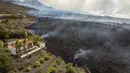 Aliran lahar menghancurkan rumah-rumah saat gunung berapi terus meletus di pulau Canary La Palma, Spanyol, Senin (29/11/2021). Beberapa ventilasi vulkanik baru dibuka di La Palma pada hari Minggu, melepaskan lava baru yang mengalir deras ke bawah. (AP/Emilio Morenatti)