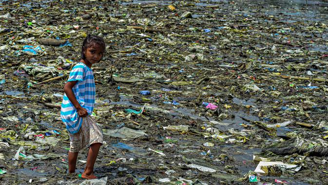 Seorang anak perempuan berjalan di tumpukan sampah di permukiman kumuh di sepanjang garis pantai Pantai Baseco di Manila (28/9/2019). Pada 12 Februari 2002, Presiden Gloria Macapagal Arroyo menyatakan Baseco sebagai tempat tinggal. (AFP Photo/Maria Tan)