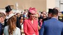 Kate Middleton, Duchess of Cambridge dari Inggris berbicara kepada para tamu di Pesta Taman Kerajaan di Istana Buckingham di London (18/5/2022). Kate Middleton mengenakan gaun mantel koral dengan topi dengan warna yang sama. (AFP/Pool/Dominic Lipinski)