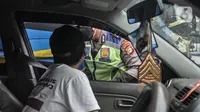 Petugas kepolisian menilang pengendara mobil yang melanggar aturan ganjil genap di Jalan MT Haryono, Jakarta, Kamis (28/10/2021). Direktorat Lalu Lintas Polda Metro Jaya mulai hari ini memberlakukan sanksi tilang kepada pelanggar ganjil genap di 13 ruas jalan DKI Jakarta. (merdeka.com/Iqbal S Nugroh