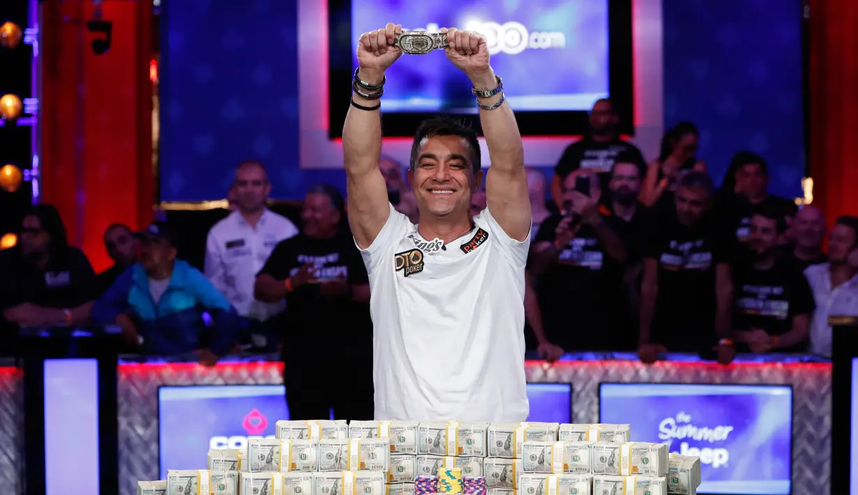 Pemain poker Hossein Ensan berpose dengan tumpukan uang sambil menunjukkan sebuah gelang usai memenangkan World Series of Poker di Las Vegas, Amerika Serikat, Rabu (17/7/2019). Pria asal Jerman tersebut mengalahkan pemain poker asal Italia, Dario Sammartino. (AP Photo/John Locher)