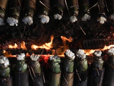 Pekerja membakar lemang atau beras ketan yang dimasukan ke bambu di kawasan Senen, Jakarta, Rabu (29/3/2023). (Liputan6.com/Herman Zakharia)