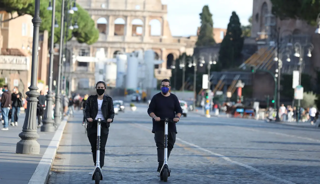 Orang-orang yang memakai masker mengendarai skuter listrik di Roma, Italia, pada 6 Oktober 2020. Pemerintah Italia juga mengumumkan situasi darurat nasional, yang pertama kali diberlakukan pada 31 Januari, akan diperpanjang "setidaknya" hingga genap satu tahun penerapannya. (Xinhua/Cheng Tingting)