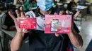 Warga menunjukkan buku tabungan dan ATM usai mengambil Bantuan Sosial Tunai (BST) di SMAN 111, Jakarta, Selasa (19/1/2021). Pemprov DKI Jakarta menyalurkan BST sebesar Rp 300 ribu kepada 1.055.216 KK mulai Januari hingga April 2021. (Liputan6.com/Faizal Fanani)