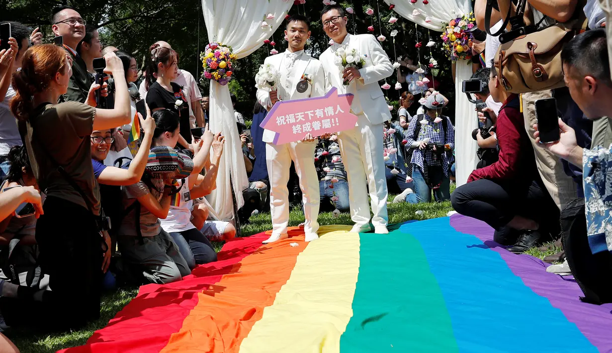 Pasangan sesama jenis berjalan di atas bendera pelangi raksasa saat melangsungkan pesta pernikahan mereka di Taipei, Taiwan, Jumat (24/5/2019). Taiwan menggelar pernikahan sesama jenis pertama di Asia. (REUTERS/Tyrone Siu)
