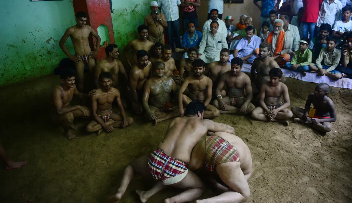Pegulat India melihat rekannya bertanding dalam pertarungan gulat tradisional menandai festival Nag Panchami, di Allahabad (15/8). Festival Hindu Nag Panchami diadakan selama musim hujan dengan berdoa. (AFP Photo/Sanjay Kanojia)
