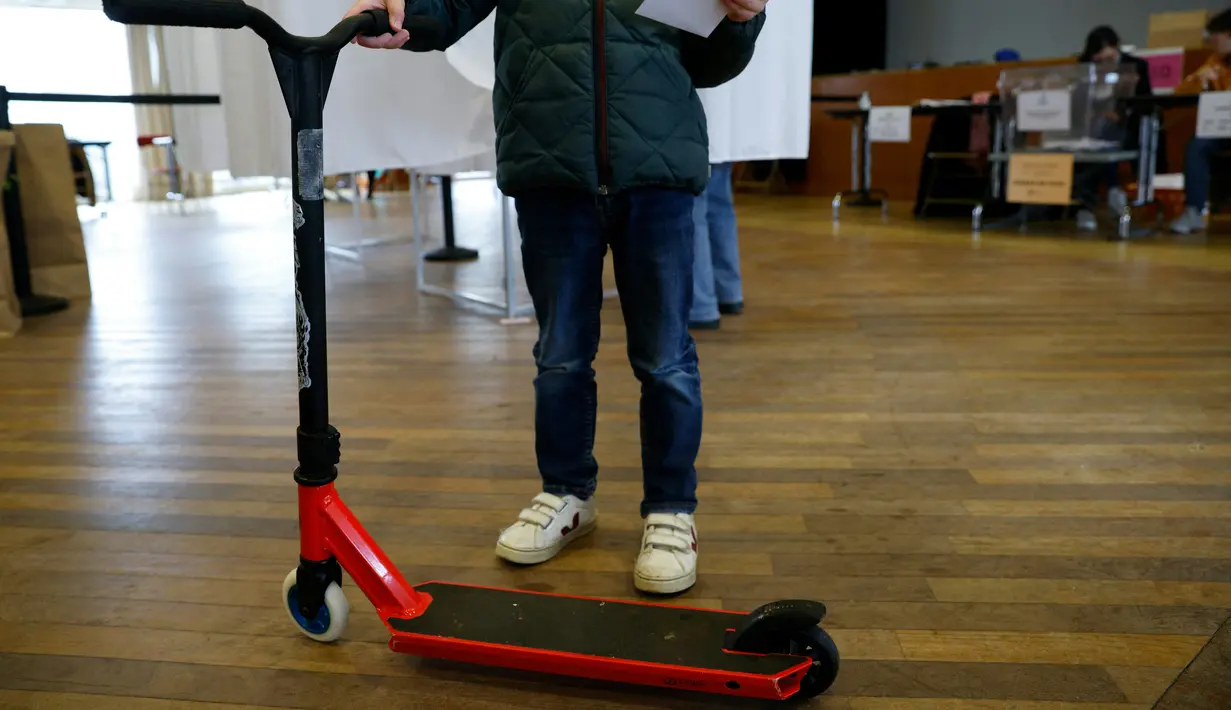 <p>Seseorang memegang surat suara dan skuter elektrik selama sesi pemungutan suara "citizen vote" untuk skuter listrik yang berseliweran di jalan, di balai kota distrik ke-17 di Paris, Minggu (2/4/2023). (Photo by Geoffroy Van der Hasselt / AFP)</p>