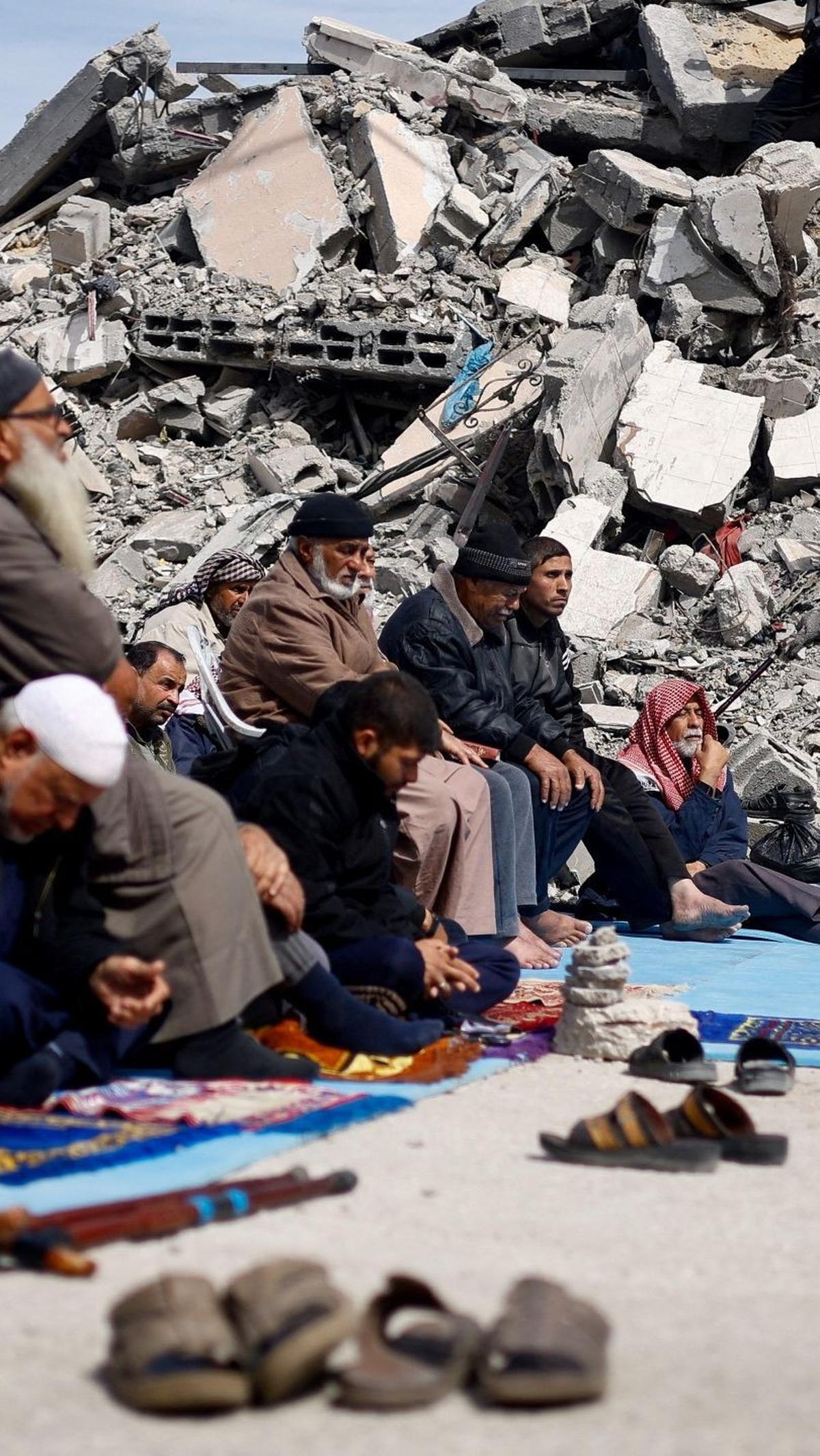 Beberapa membawa sajadah, sementara yang lain hanya duduk di atas aspal dan tanah yang hancur. Foto: REUTERS / Mohammed Salem<br>