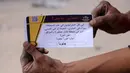 Seorang pria Palestina memegang selebaran yang dibagikan oleh tentara Israel pada 22 Mei 2025. (BASHAR TALEB/AFP)