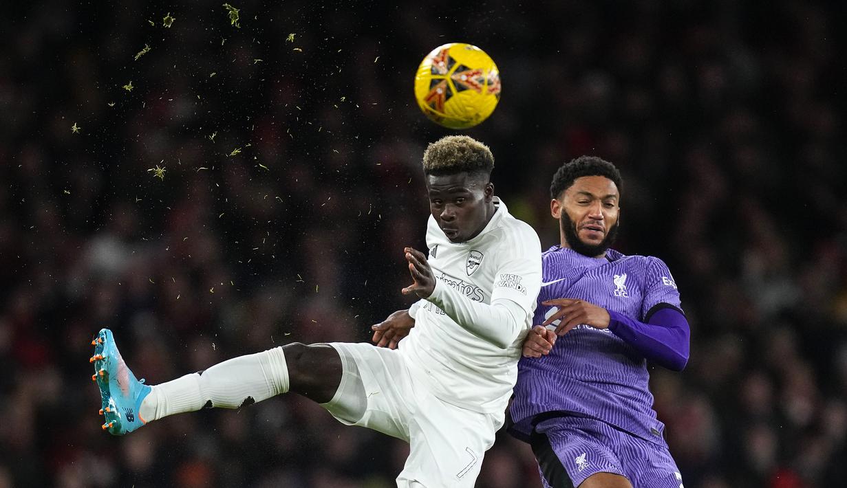 Pemain Arsenal, Bukayo Saka (kiri) berebut bola dengan pemain Liverpool, Joe Gomez saat laga putaran ketiga Piala FA 2023/2024 di Emirates Stadium, London, Inggris, Minggu (07/01/2024) WIB. Ini merupakan musim ketiga Arsenal menggunakan seragam yang meniadakan warna merah tradisional klub sejak 2022. (AP Photo/Kirsty Wigglesworth)