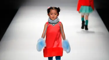 Seorang anak berjalan di atas catwalk memperagakan karya desainer Amelie Wang pada China Fashion Week di Beijing,  31 Oktober 2017. (AP Photo/Andy Wong)