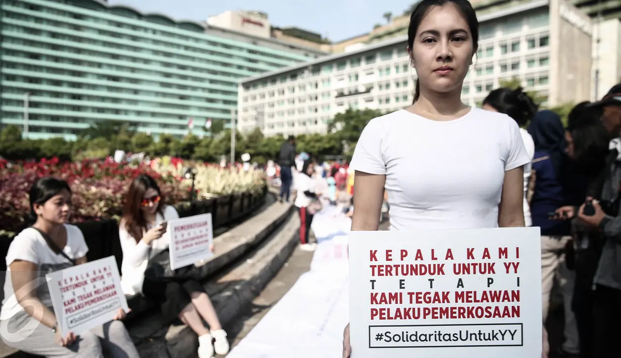 Seorang peserta aksi memegang poster disela kegiatan car free day di Bundaran HI, Jakarta, Minggu (8/5). Aksi itu merupakan solidaritas serta bentuk kecaman terhadap kekerasan seksual yang menimpa pelajar Bengkulu, Yuyun (14). (Liputan6.com/Faizal Fanani)