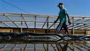 Seorang petani berjalan di samping bak garam yang sedang diproses dengan cara tradisional di sebuah tambak di Lamnga, pinggiran Banda Aceh, Aceh, Selasa (7/3/2023). Kebutuhan garam industri di Aceh saat ini dipasok dari agen di Provinsi Sumatera Utara dan Pulau Jawa. (CHAIDEER MAHYUDDIN/AFP)