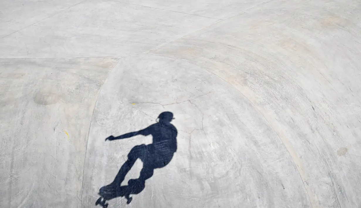 Aksi atlet Skateboard pria terlihat dalam siluet selama berkompetisi dalam Olimpiade Tokyo 2020 di Ariake Sports Park Skateboarding di Tokyo, Jepang, Kamis (5/8/2021). (AFP/Loic Venance)