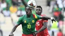 Pemain depan Kamerun Vincent Aboubakar (kiri) ditantang oleh bek Gambia James Gomez pada pertandingan perempatfinal Piala Afrika 2021 di Japoma Stadium, Minggu (30/1/2022) dini hari WIB. Kamerun melangkah ke semifinal usai menang atas Gambia, 2-0. (CHARLY TRIBALLEAU / AFP)