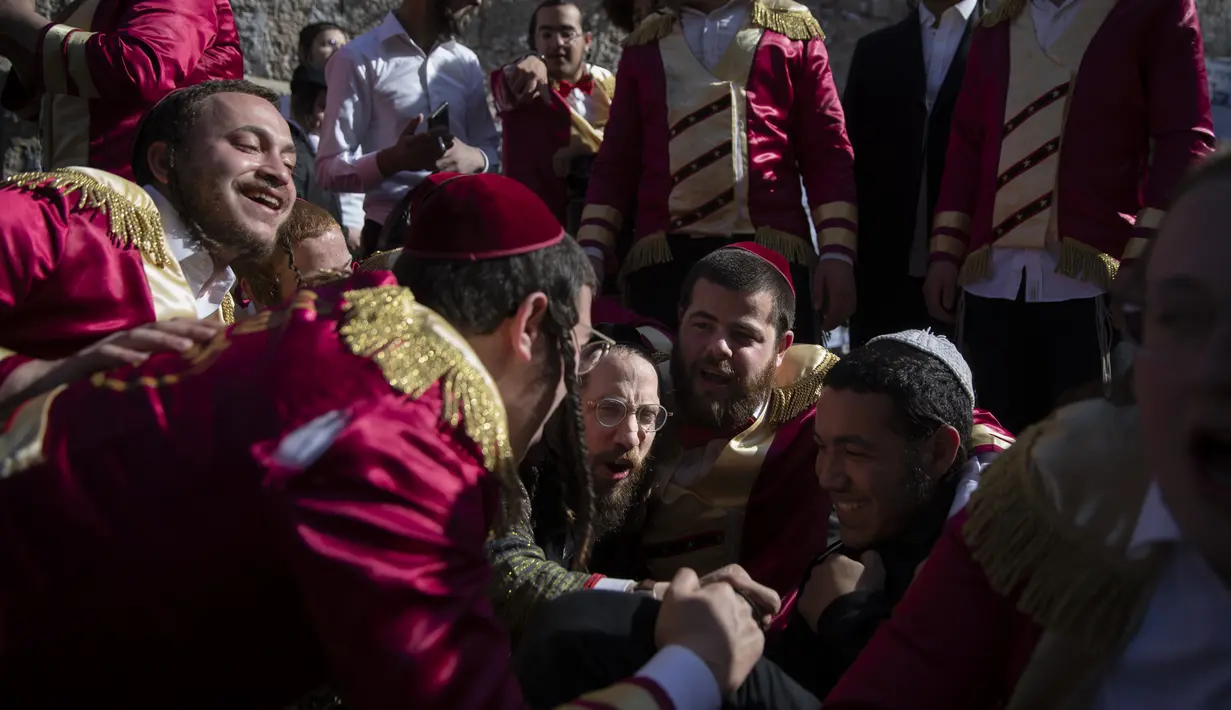 Yahudi Ultra-Ortodoks merayakan setelah minum alkohol selama hari libur Yahudi Purim di ultra-Ortodoks Mea Shearim, Yerusalem (28/2/2021). Hari libur Purim Yahudi memperingati keselamatan orang Yahudi dari genosida di Persia kuno, seperti yang diceritakan dalam Kitab Ester. (AP Photo/Oded Balilty)