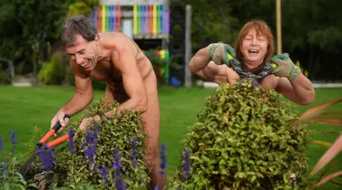 Brent Anderson (kiri) dan Robyn Beach memangkas tanaman saat berpartisipasi dalam World Naked Gardening Day di Wellington Naturist Club di Upper Hutt, Wellington , Selandia Baru (5/5). Acara ini sudah ada sejak 2015. (AFP Photo/Marty Melville)