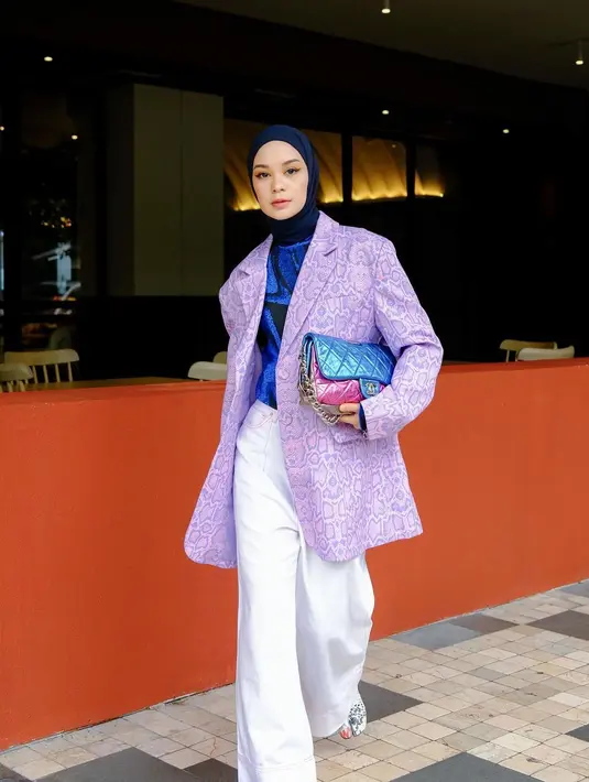 Tantri Namirah tampil keren memadukan blouse silk biru navy dengan oversized blazer bernuansa ungu dengan corak berpola, celana panjang putih, dan shoulder bag bernuansa nila. [Foto: Instagram/tantrinamirah]