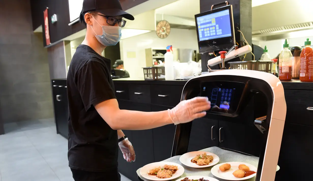 Pelayan memasukkan nomor meja untuk pengantaran robot di restoran Asia di Wina, Austria, Kamis (28/5/2020). Restoran tersebut menggunakan robot untuk mengantar makanan guna mengurangi kontak yang tidak diperlukan antara pelayan dan pelanggan di tengah pandemi virus corona COVID-19. (Xinhua/Guo Chen)