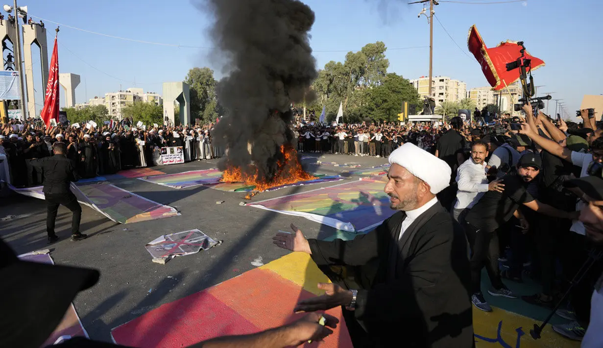 <p>Pendukung pemimpin Syiah Moqtada Sadr membakar bendera pelangi saat demonstrasi di depan Kedutaan Besar Swedia, Baghdad, Irak, Jumat (30/6/2023). Aksi tersebut dilakukan sebagai bentuk protes atas pembakaran Alquran di Swedia. (AP Photo/Hadi Mizban)</p>
