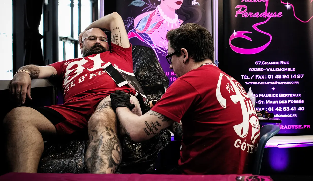 Seorang pria membuat tato di pahanya saat Paris Tattoo Convention di Grand Halle de la Villette, Paris, Prancis, Jumat (9/3). Paris Tattoo Convention tahun ini merupakan yang kedelapan. (Philippe LOPEZ/AFP)