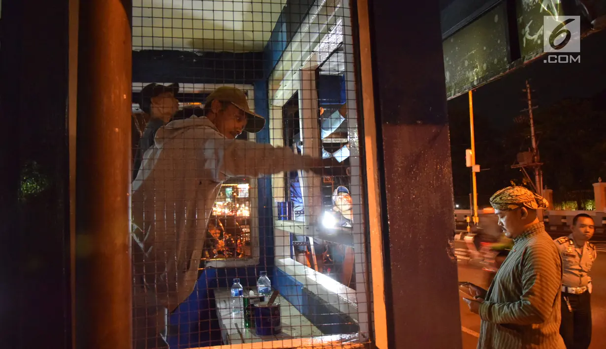 Petugas dibantu warga memperbaiki pos polisi yang sebelumnya dibakar massa saat peringatan Hari Buruh di Yogyakarta, Selasa (1/5) malam. Aksi ini menyebabkan kericuhan antara polisi, warga sekitar dan pendemo. (Liputan6.com/Gholib)