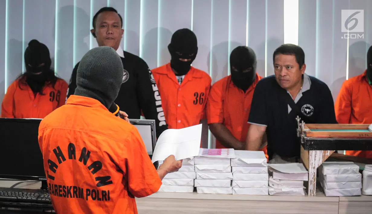 Seorang tersangka menunjukan proses pembuatan uang palsu saat rilis di Bareskrim Polri, Jakarta, Rabu (18/10). Barang bukti uang palsu tersebut terdiri dari 313 lembar potongan kertas. (Liputan6.com/Faizal Fanani)