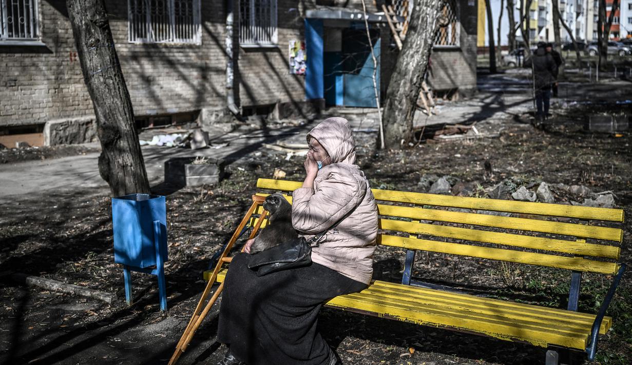 Seorang wanita menangis saat dia duduk di luar sebuah bangunan yang rusak akibat pemboman di Kota Kharkiv, Ukraina timur, 24 Februari 2022. Angkatan bersenjata Rusia melancarkan invasi militer ke Ukraina. (Aris Messinis/AFP)