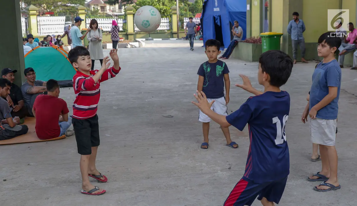 Anak-anak pencari suaka bermain bola voli di halaman bekas Markas Kodim di Kalideres, Jakarta, Selasa (16/7/2019). Sejak Kamis (11/7) para pencari suaka dipindahkan dari di pinggir jalan dan trotoar di kawasan Kebon Sirih ke bekas Markas Kodim di Kalideres . (Liputan6.com/Helmi Fithriansyah)