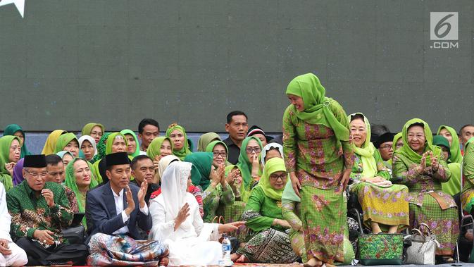 Ketua Umum PP Muslimat NU Khofifah Indar Parawansa tersenyum ke arah Presiden Joko Widodo atau Jokowi saat akan memberi sambutan dalam Harlah ke-73 Muslimat NU di SUGBK, Jakarta, Minggu (27/1). (Liputan6.com/Johan Tallo)