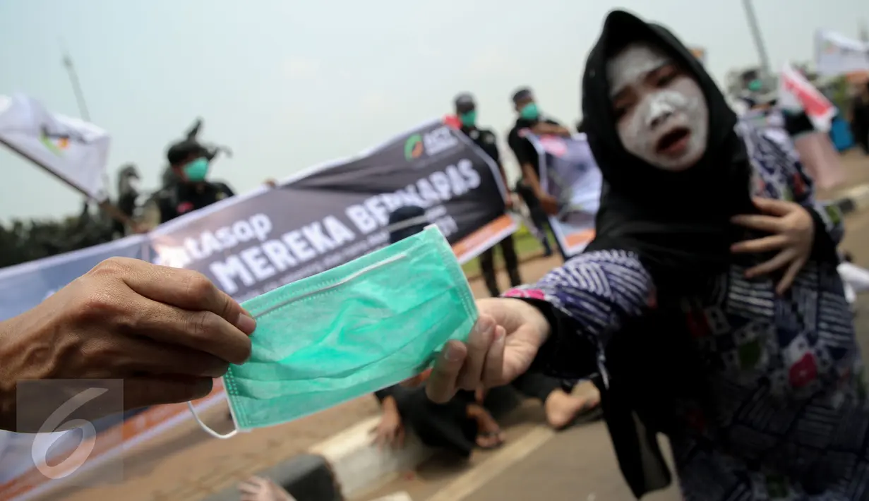 Massa dari Aksi Cepat Tanggap (ACT) melakukan teatrikal saat aksi menolak asap di Patung Kuda, Jakarta, Senin (26/10). Aksi itu menuntut elemen masyarakat agar terlibat langsung dalam upaya penuntasan masalah asap. (Liputan6.com/Faizal Fanani)