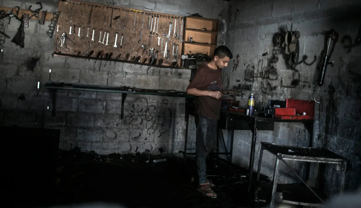 Mohammed (15) menyelesaikan pekerjaannya sebagai mekanik di Rafah, Selatan Jalur Gaza, 21 November 2016. Tercatat 80% penduduk Gaza hidup mengandalkan bantuan (charity) dan angka pengangguran di Gaza 45% tertinggi di dunia. (SAID KHATIB/AFP)