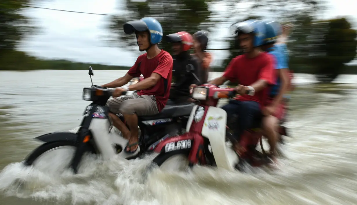 Pengendara motor melintasi jalan yang terkena banjir di kawasan Jal Besar, Malaysia, Kamis (5/1). Sekitar 23 ribu orang terpaksa mengungsi karena banjir yang disebabkan hujan muson ini. (AFP PHOTO / MOHD RASFAN)