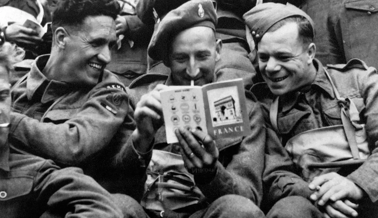 Sambil bercanda, beberapa tentara Inggris melihat dan membaca buku panduan wisata tentang Perancis disebuah kapal pendarat, (6/6/1944). (AFP PHOTO)