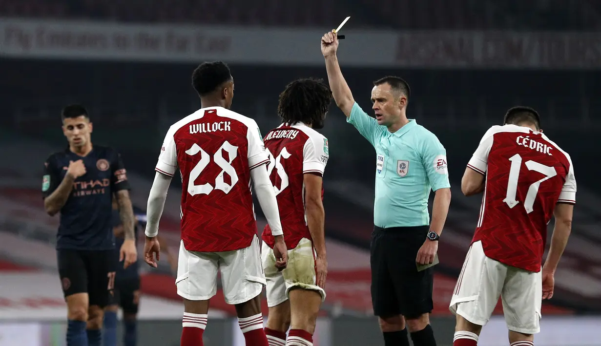 Gelandang Arsenal, Mohamed Elneny (tengah), menerima kartu kuning dari wasit Stuart Atwell dalam laga perempatfinal Piala Liga Inggris Carabao Cup melawan Manchester City di Emirates Stadium, London, Selasa (22/12/2020). Arsenal kalah 1-4 dari Manchester City. (AFP/Adrian Dennis)
