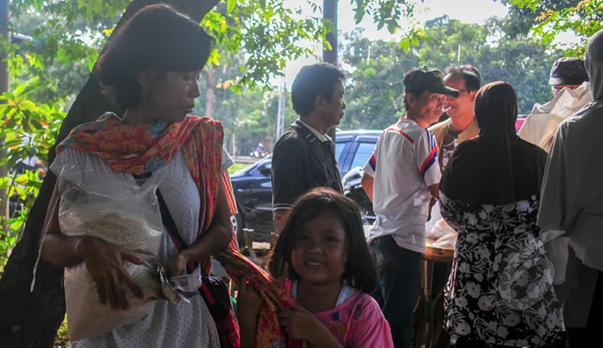 Seorang anak tersenyum usai ibunya berhasil membeli beras saat operasi pasar beras oleh BULOG di Lenteng Agung, Jakarta, Senin (2/3/2015). Operasi ini digelar sebagai upaya menurunkan harga beras yang terus naik.(Liputan6.com/Yoppy Renato)